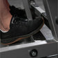 Black mesh lace-up sneaker with brown sole, worn by model on exercise equipment
