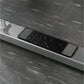Black and silver textured plate-loaded row machine nameplate on white ledge with dark tile background