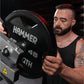 Man using black Hammer Strength plate-loaded rowing machine with 45-pound weight plates loaded, worn by model in black tank t