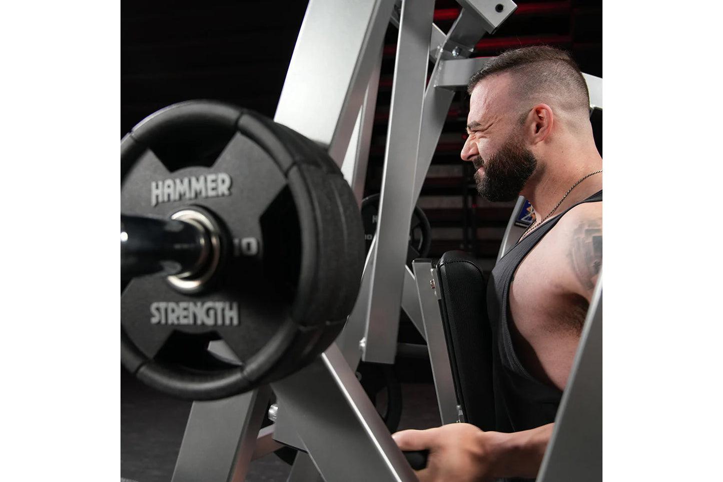 Man using Hammer Strength plate-loaded iso-lateral row machine with black weight plate, commercial gym equipment