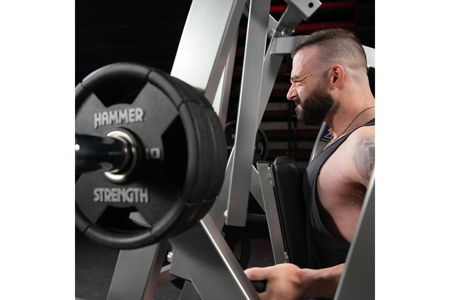 Man using Hammer Strength plate-loaded iso-lateral row machine with black weight plate, commercial gym equipment
