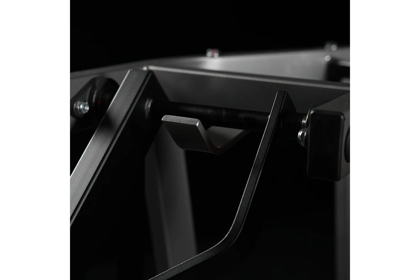 Black plate-loaded chest press machine with dual handles and metal frame detail, close-up side view on white background
