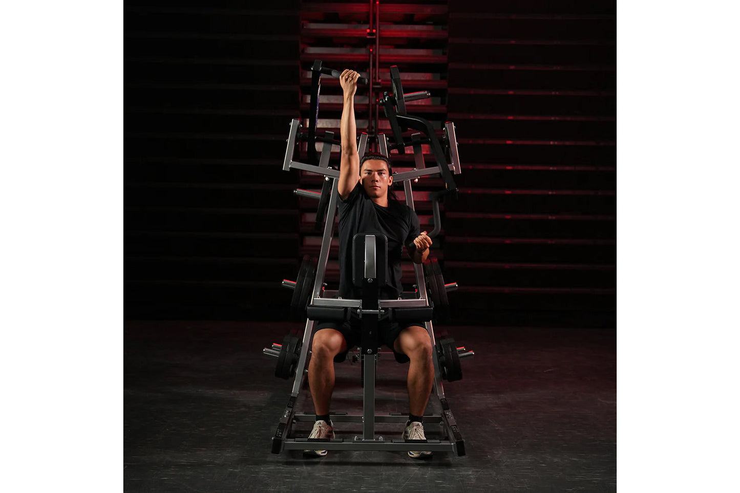 Man using black and red Hammer Strength plate-loaded lat pulldown machine, performing front pull exercise in gym setting