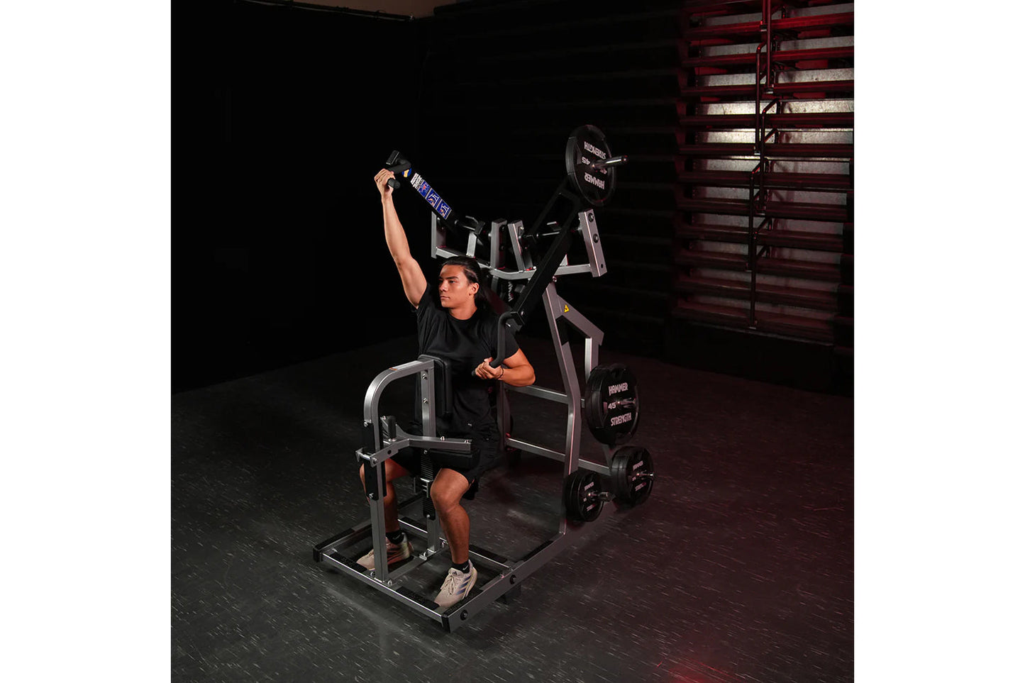 Man in black shirt using Hammer Strength plate-loaded iso-lateral front lat pulldown machine in gym setting