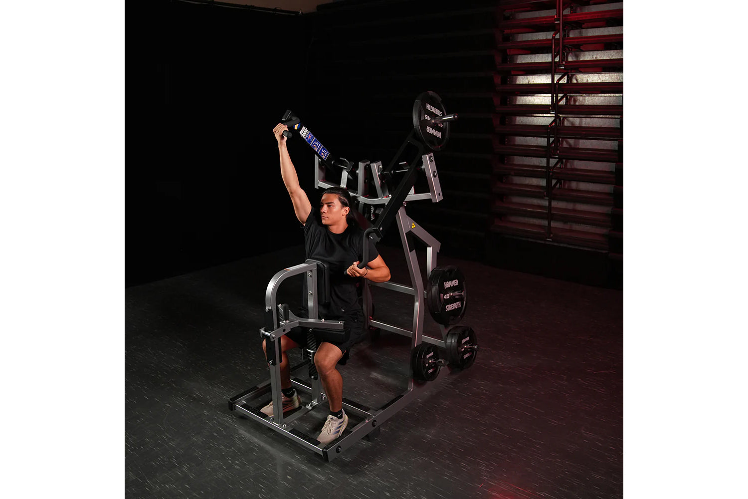 Man in black shirt using Hammer Strength plate-loaded iso-lateral front lat pulldown machine in gym setting