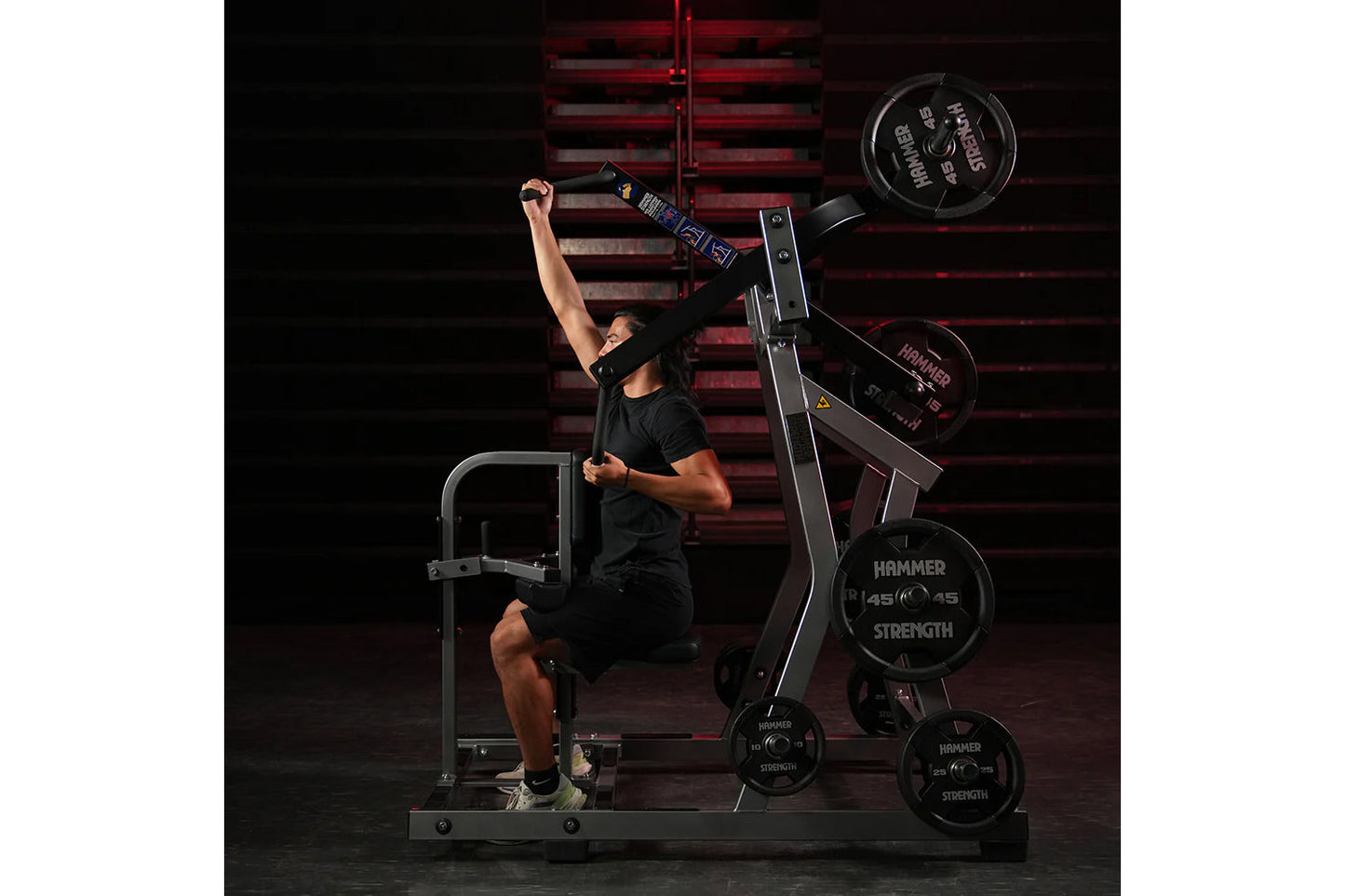 Male athlete using Hammer Strength plate-loaded lat pulldown machine with black weight plates, demonstrating exercise form in