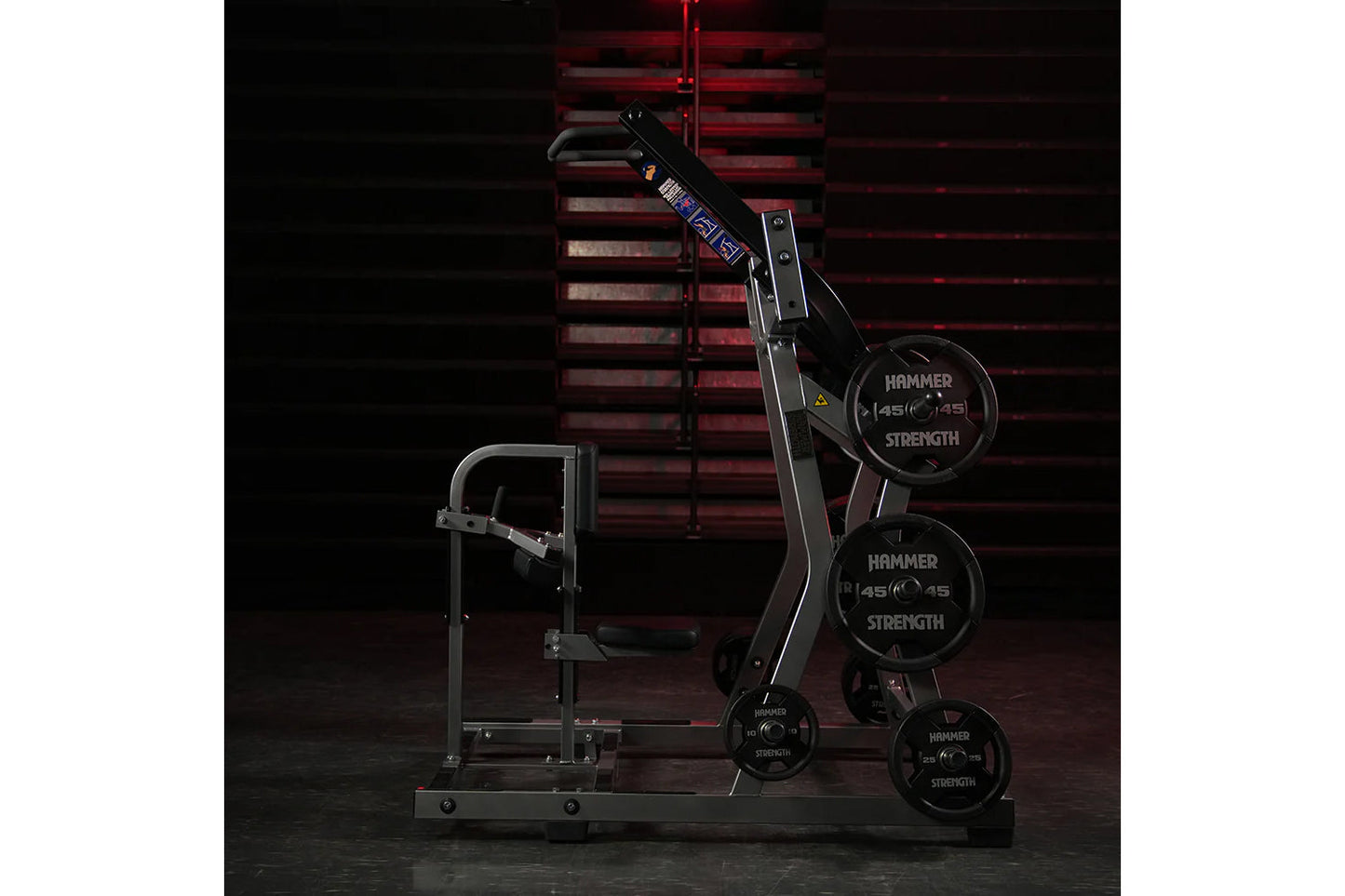 Hammer Strength black plate-loaded iso-lateral front lat pulldown machine with weight plates loaded, front view against red b