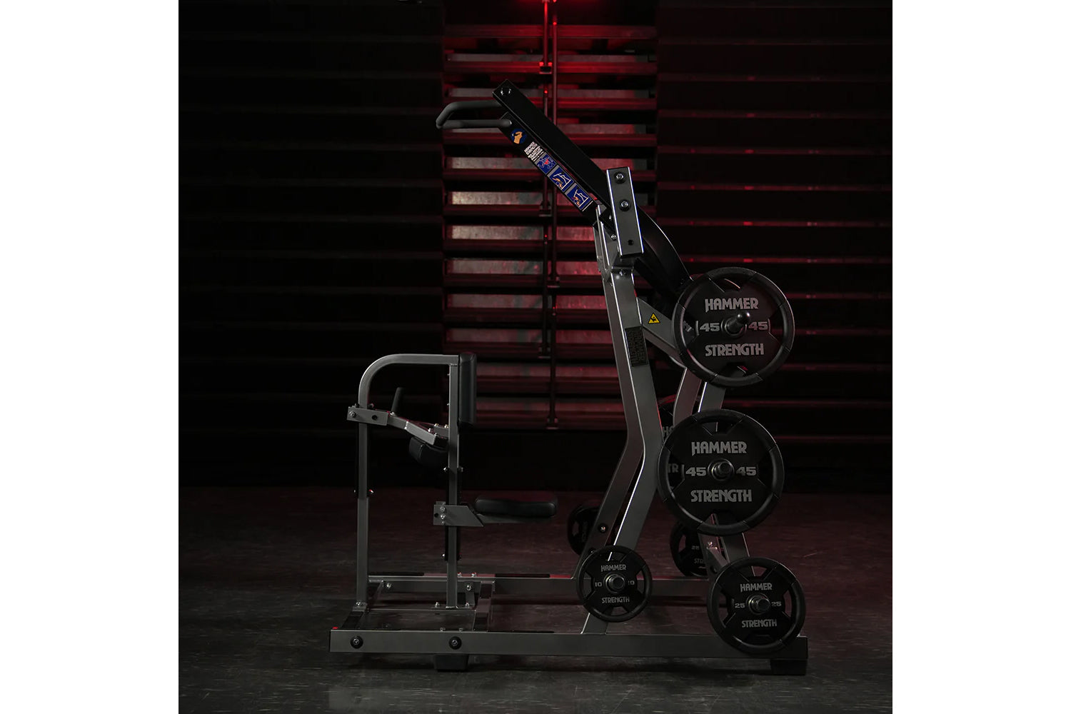 Hammer Strength black plate-loaded iso-lateral front lat pulldown machine with weight plates loaded, front view against red b