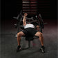 Man using black Hammer Strength plate-loaded chest press machine in gym, wearing white tank top and black shorts