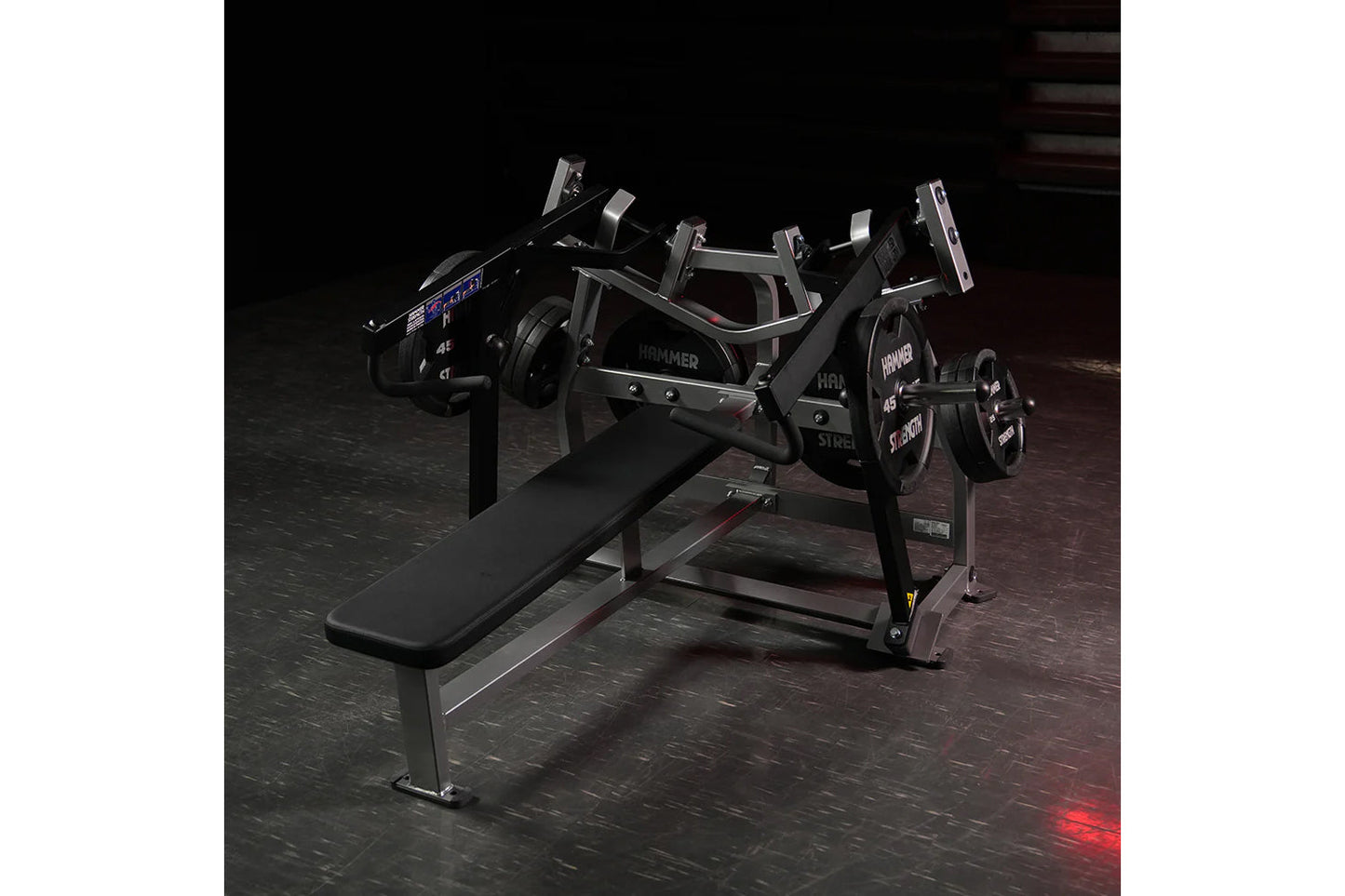 Hammer Strength black plate-loaded iso-lateral horizontal bench press with dual foot pedals, on dark gym floor
