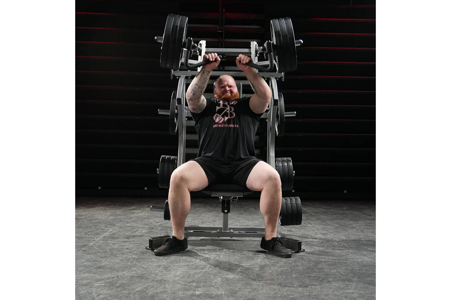 Man wearing black t-shirt performing incline chest press on Hammer Strength plate-loaded machine with black weight plates in 