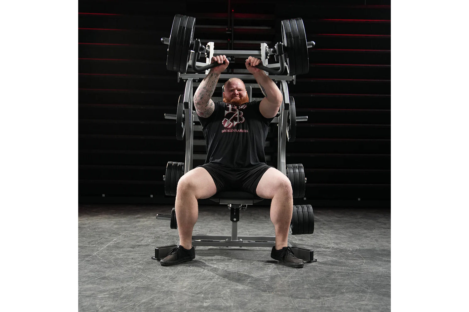Man wearing black t-shirt performing incline chest press on Hammer Strength plate-loaded machine with black weight plates in 