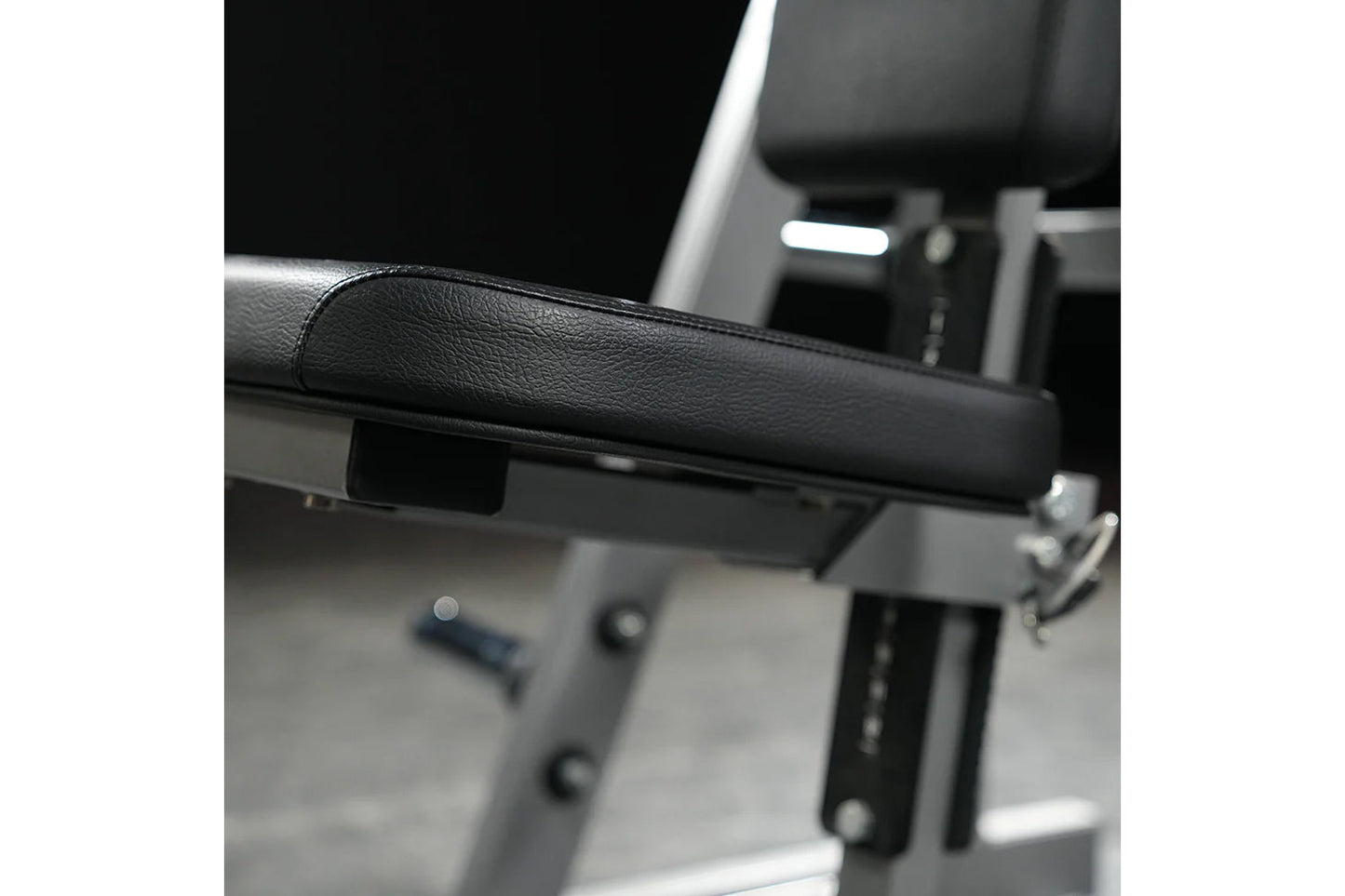 Black leather padded handle on weight training machine with gray metal frame and adjustment mechanisms