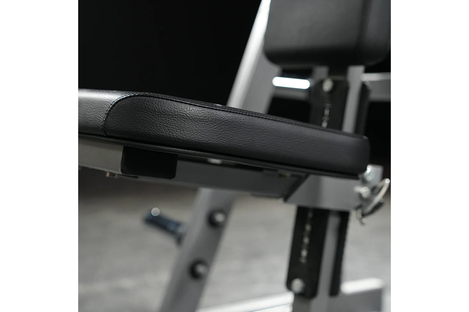 Black leather padded handle on weight training machine with gray metal frame and adjustment mechanisms