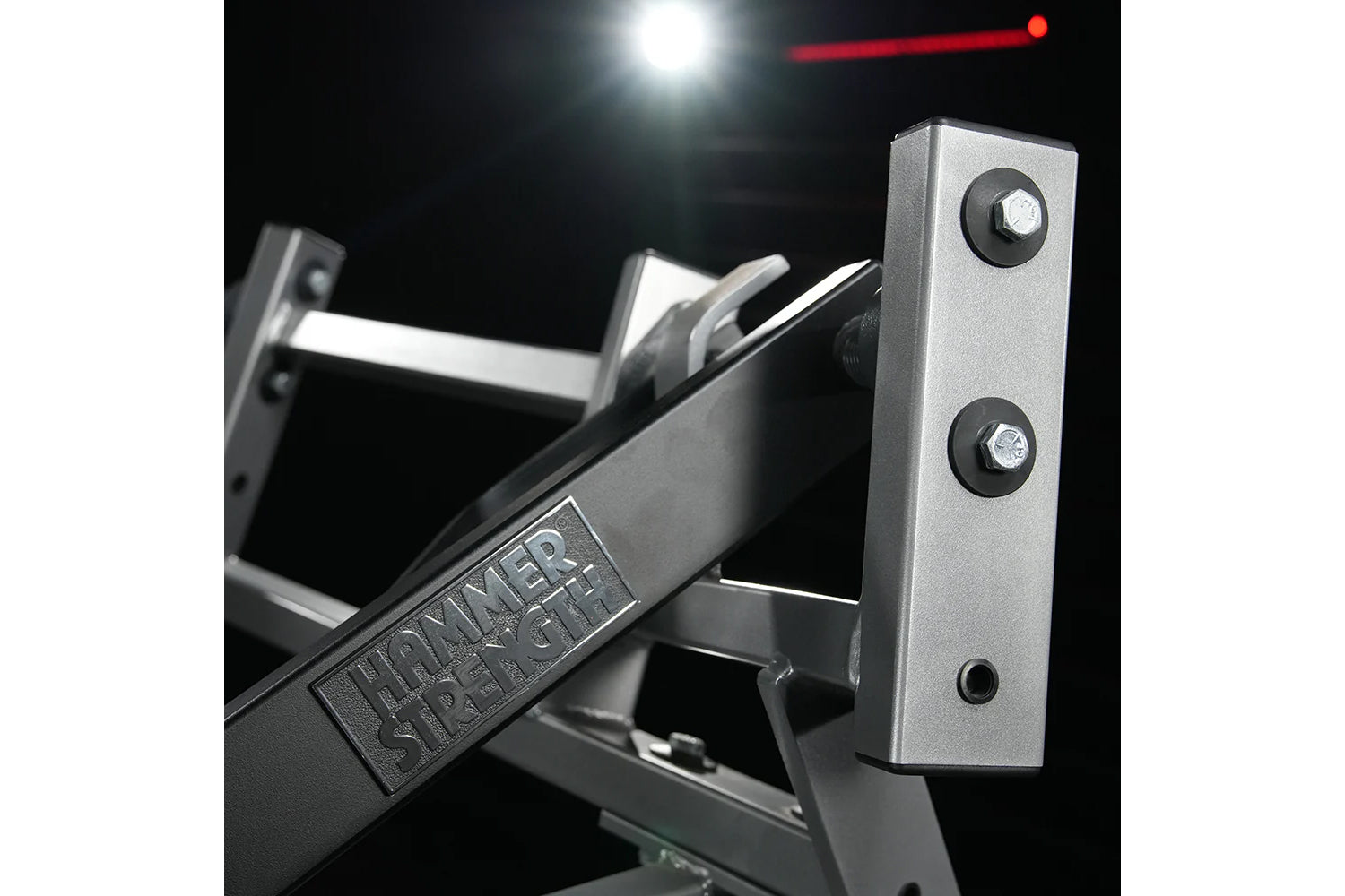 Hammer Strength plate-loaded iso-lateral incline press with silver metallic frame and black handles against dark background