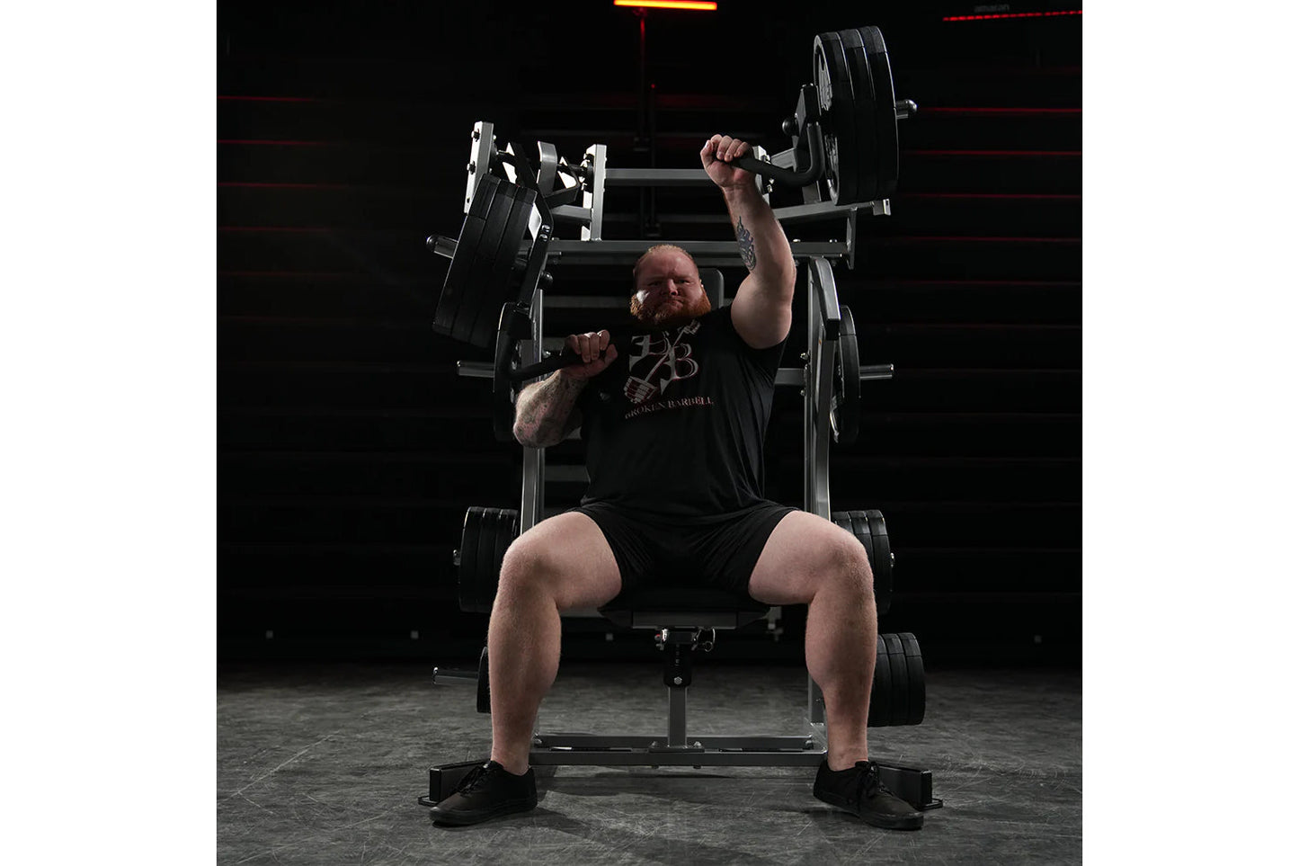 Man performing incline chest press on black Hammer Strength plate-loaded machine in gym setting