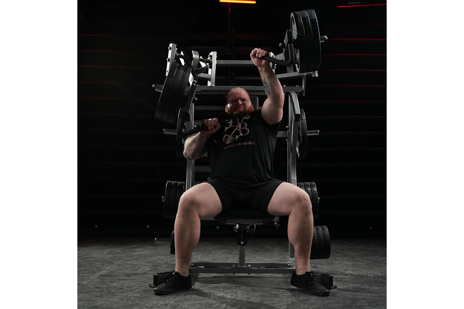 Man performing incline chest press on black Hammer Strength plate-loaded machine in gym setting