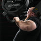 Man with red beard wearing black cap and shirt lifting heavy black dumbbell in gym setting