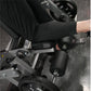 Person using black and gray plate-loaded leg curl machine with padded arm rests and adjustable seat, viewed from above