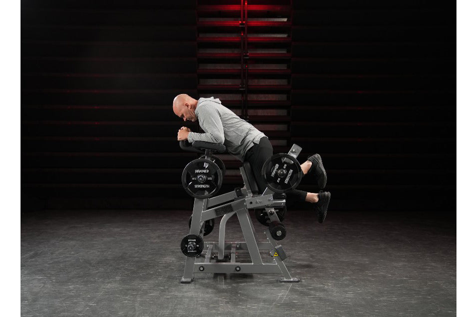 Man using Hammer Strength plate-loaded iso-lateral kneeling leg curl machine in gym setting