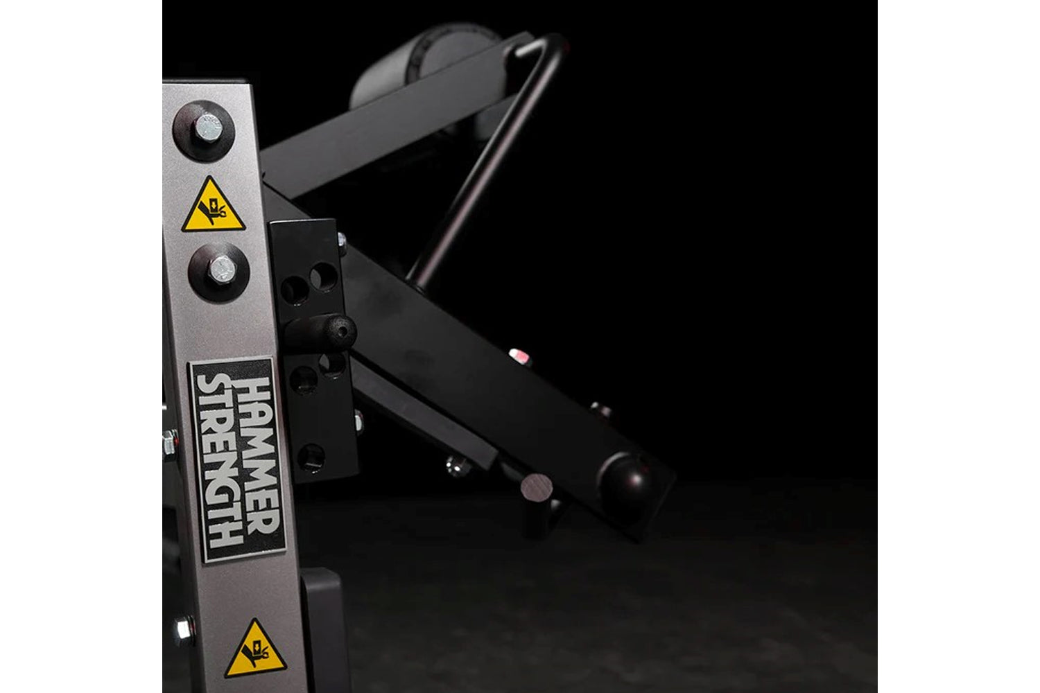 Hammer Strength plate-loaded leg curl machine with gray and black frame, dual control handles, and yellow caution decals on b