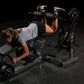 Woman performing leg curl exercise on black Hammer Strength plate-loaded machine with dumbbells, demonstrating proper form an