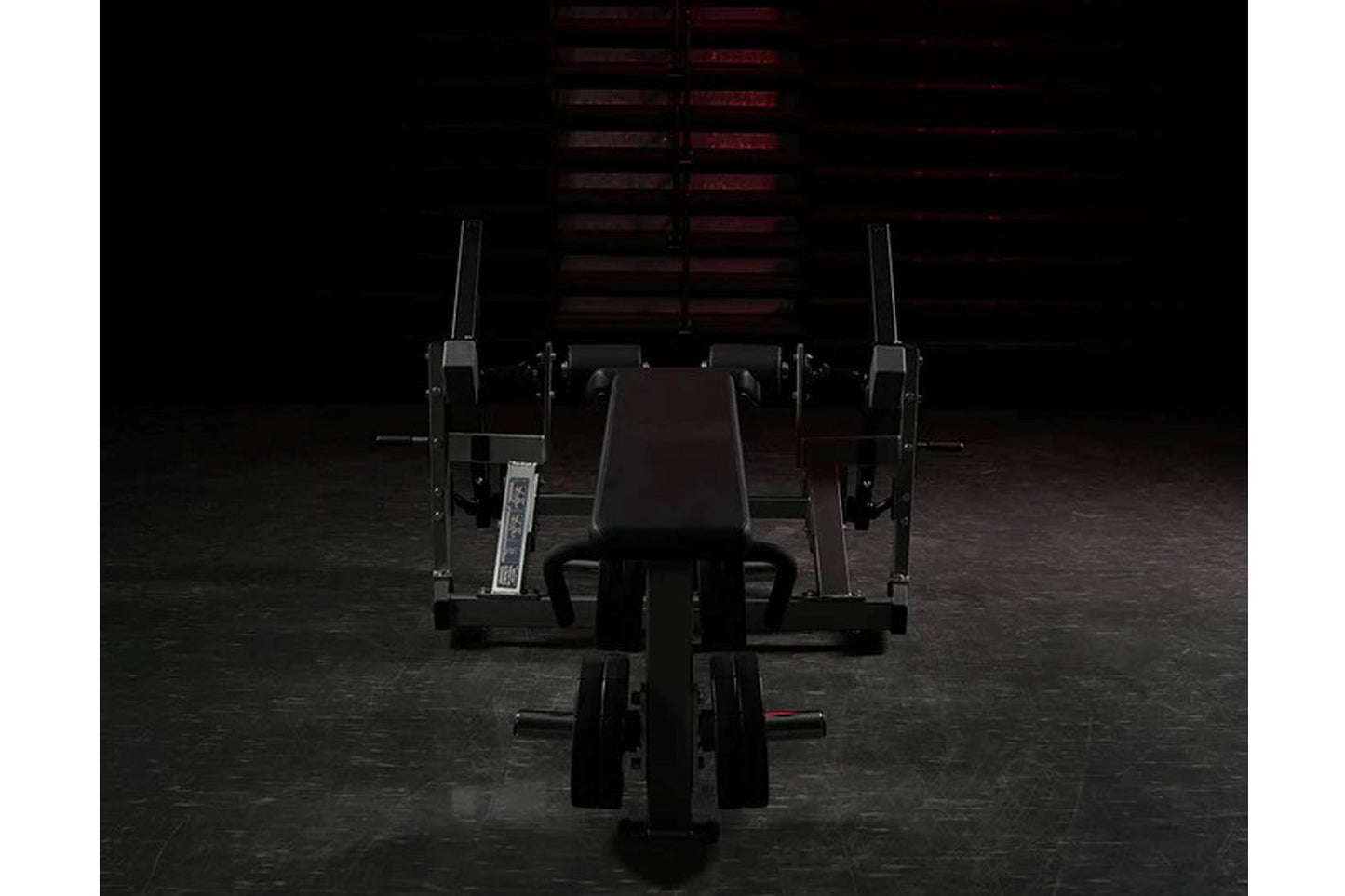 Black plate-loaded iso-lateral leg curl machine with padded seat and dual leg extension arms in gym setting