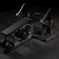 Black Hammer Strength plate-loaded leg curl machine with padded seat, weight plates, and dual lever arms on dark gym floor