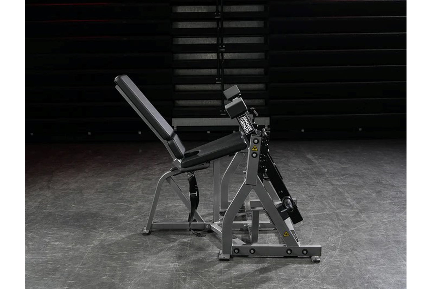 Hammer Strength plate-loaded iso-lateral leg extension machine with gray frame, black padded seat, and digital display on gym