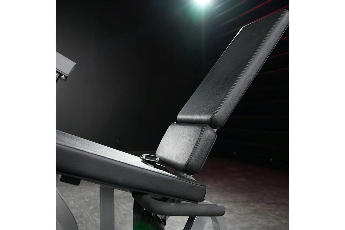 Black leather and metal leg extension machine with padded seat and armrests, displayed in gym setting under studio lighting