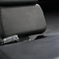 Black padded leg extension machine seat with metal adjustment lever and textured leather surface