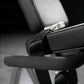 Black padded leg extension machine seat and armrest with metal adjustment lever, closeup detail