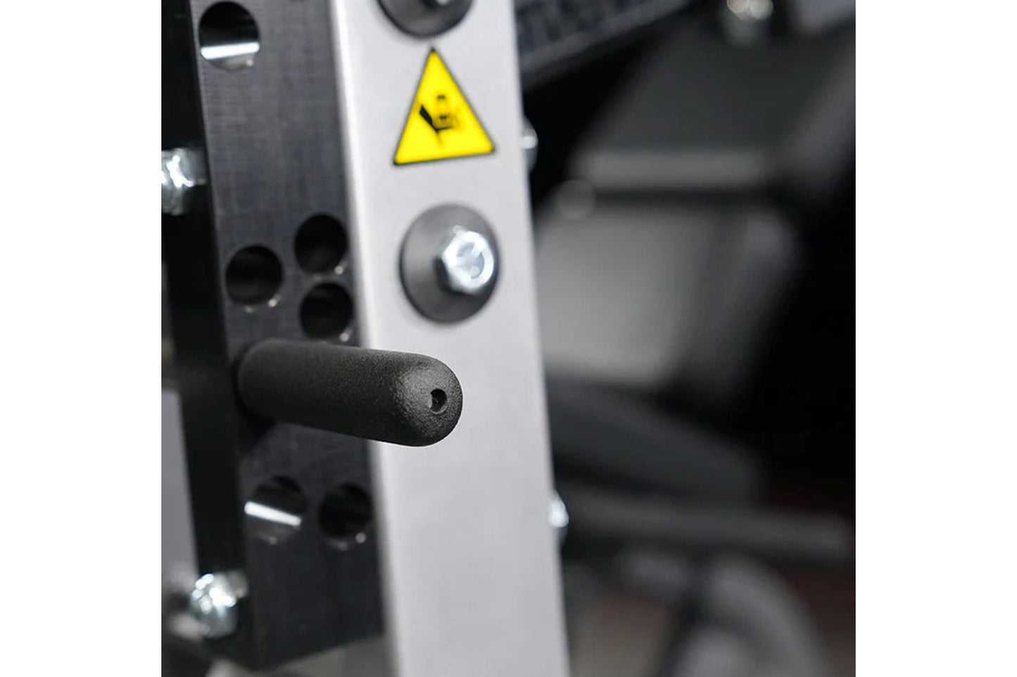 White and black Hammer Strength leg extension machine with yellow caution triangle and control buttons, close-up detail view