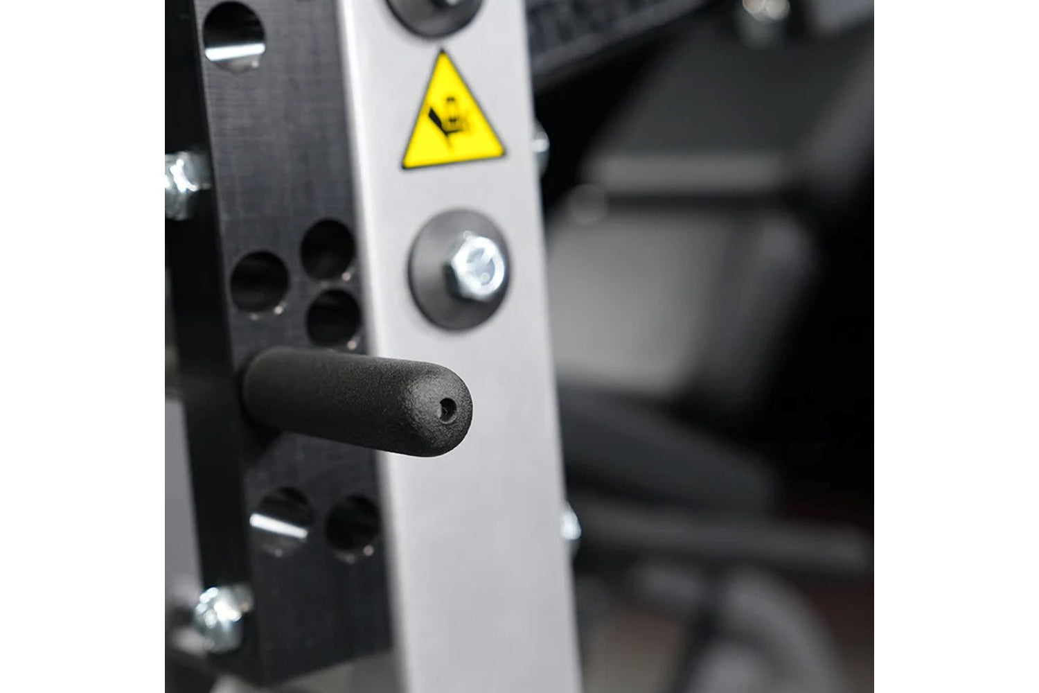 White and black Hammer Strength leg extension machine with yellow caution triangle and control buttons, close-up detail view