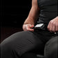 Person in black athletic wear using plate-loaded leg extension machine with white label on black frame