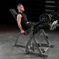Man using black plate-loaded leg extension machine with loaded barbell in gym setting