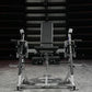 Black and silver plate-loaded leg extension machine with padded seat and dual leg extension arms, front view on gray concrete