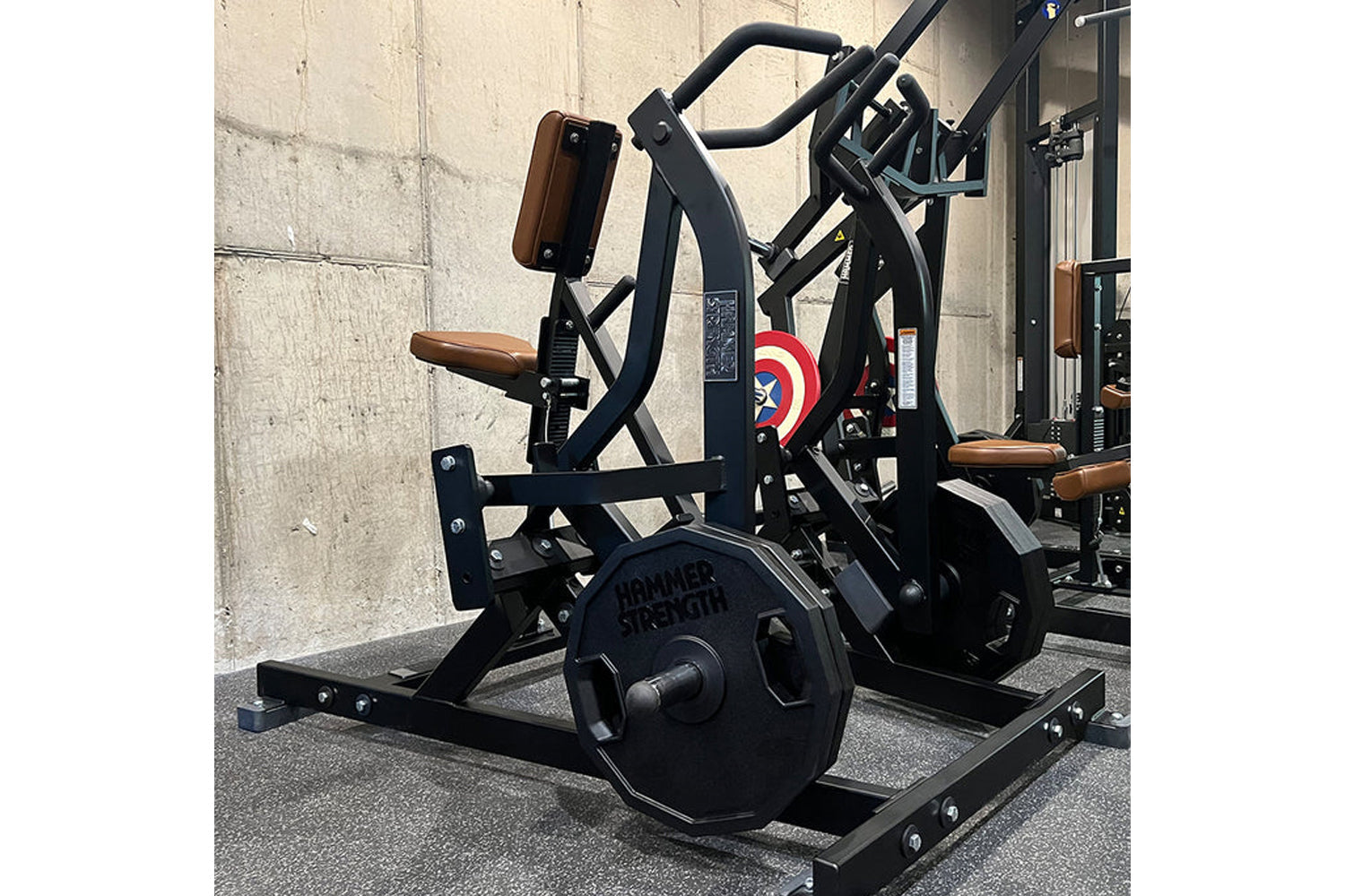 Black plate-loaded iso-lateral row machine with brown leather seat and handles in gym setting