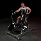 Man using black Hammer Strength plate-loaded iso lateral row machine, wearing gray t-shirt and black shorts on dark gym floor