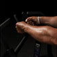 Man gripping black handles of Hammer Strength plate-loaded iso lateral row machine, wearing white wristband, demonstrating pr