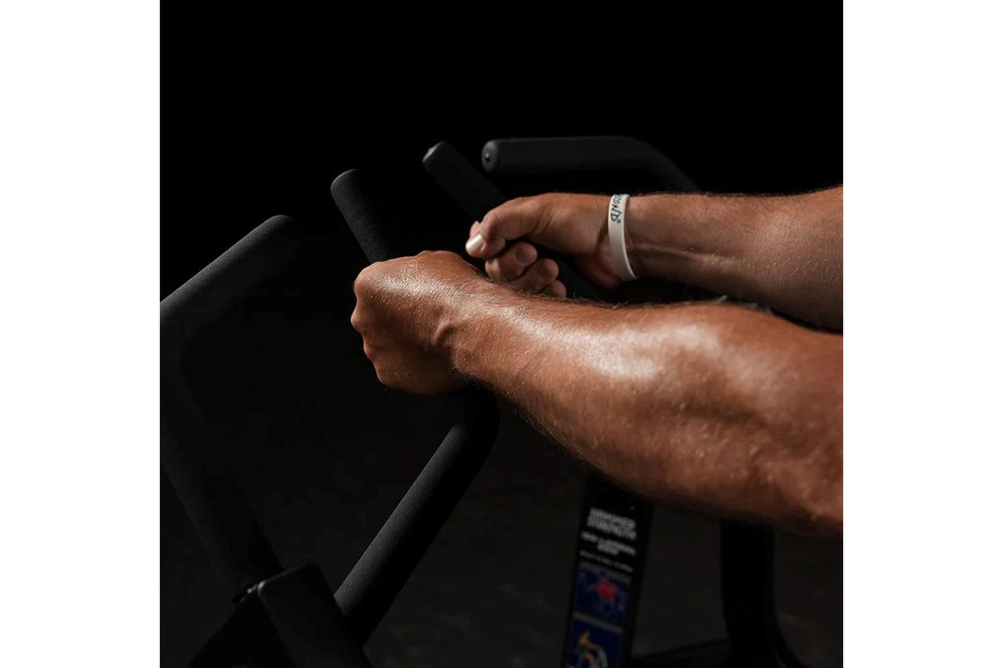 Man gripping black handles of Hammer Strength plate-loaded iso lateral row machine, wearing white wristband, demonstrating pr