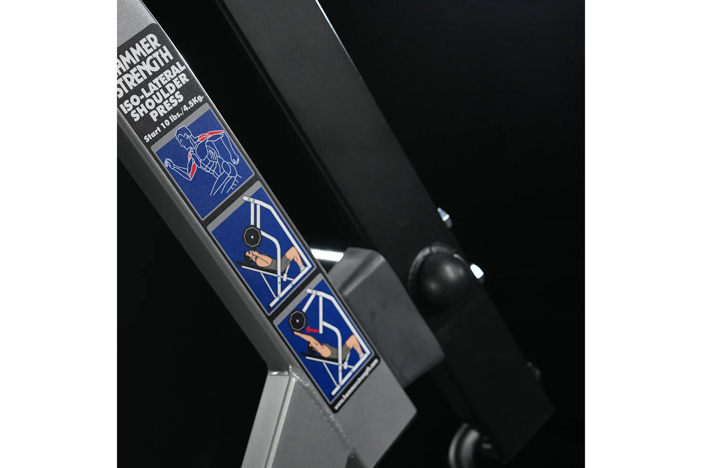 Hammer Strength plate-loaded iso-lateral shoulder press machine with blue instruction decals and gray frame, close-up detail 