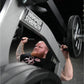 Athlete with red beard and tattoos performing shoulder press on Hammer Strength plate-loaded machine with black weight plates