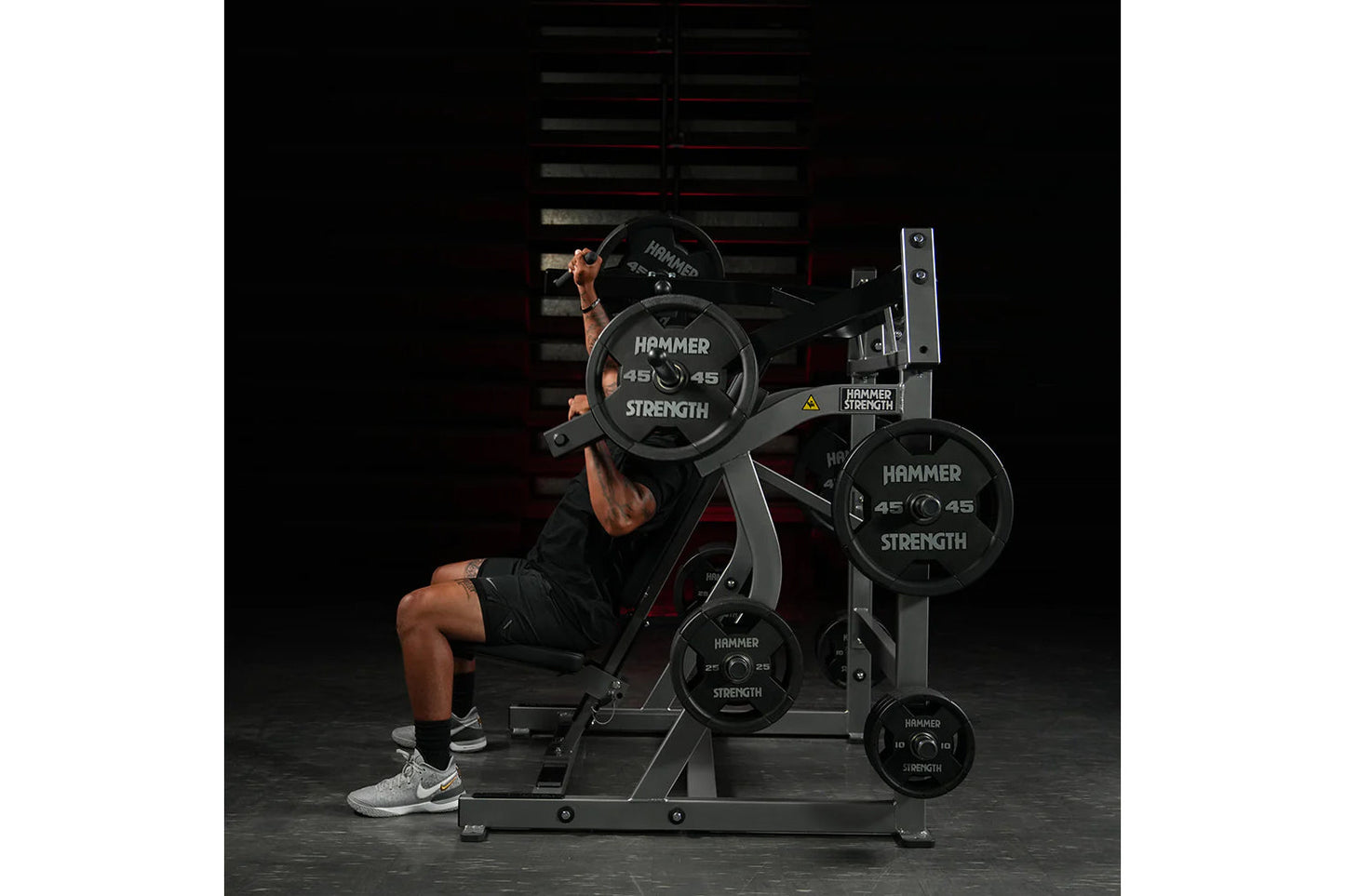 Man using Hammer Strength plate-loaded iso-lateral super incline press with 45-pound weight plates in gym setting