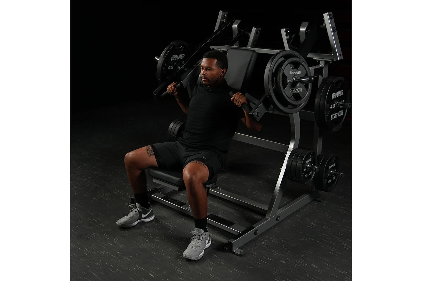 Man using black Hammer Strength plate-loaded iso-lateral super incline press with loaded weight plates in gym setting