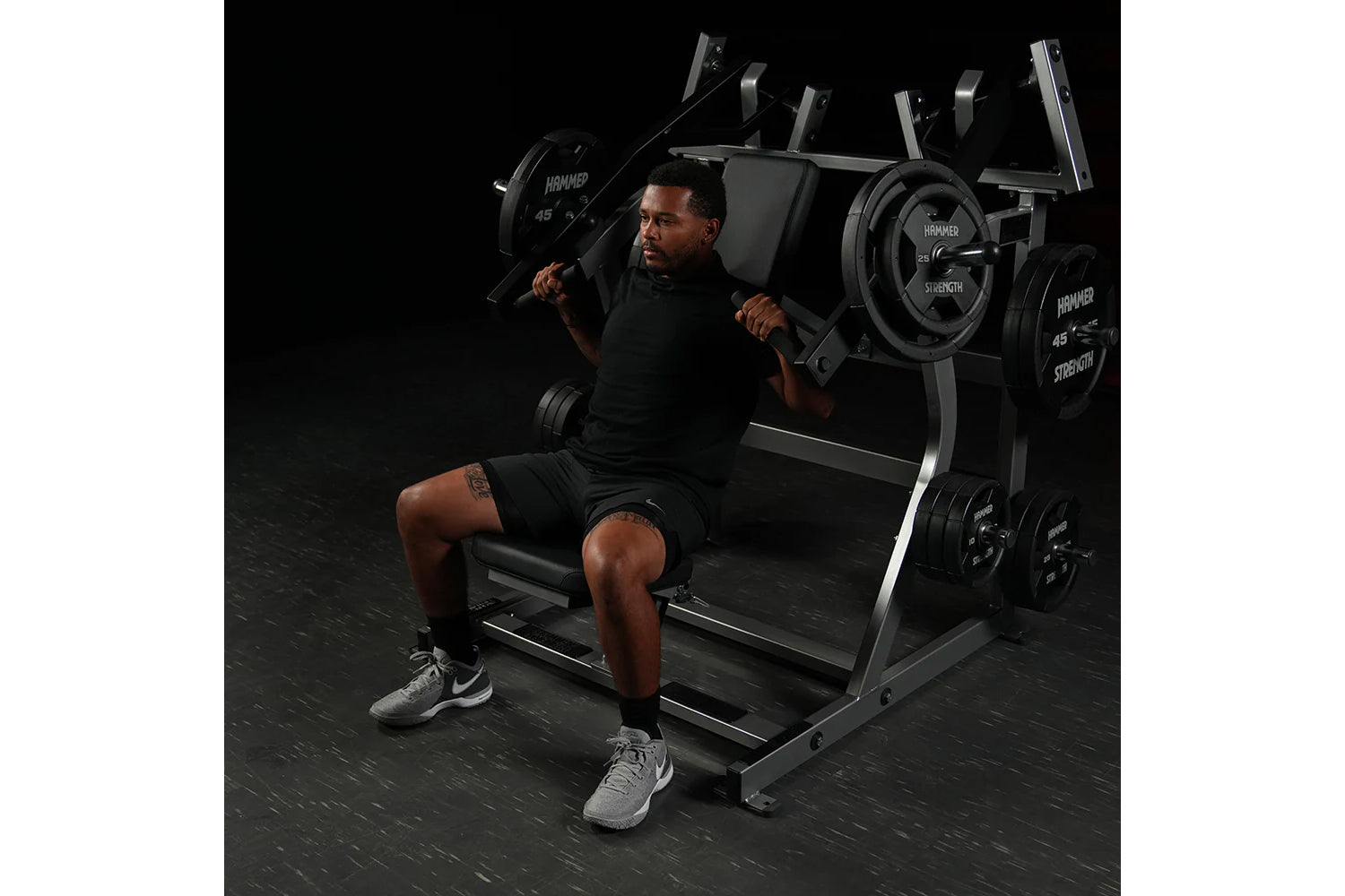 Man using black Hammer Strength plate-loaded iso-lateral super incline press with loaded weight plates in gym setting