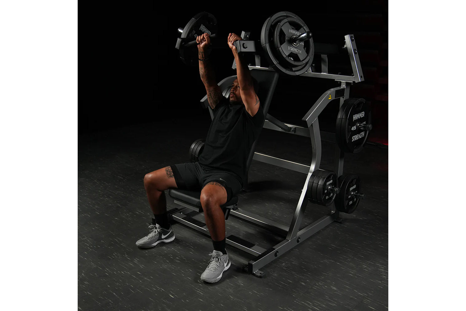 Man using black Hammer Strength plate-loaded incline press with dumbbells, demonstrating chest exercise form