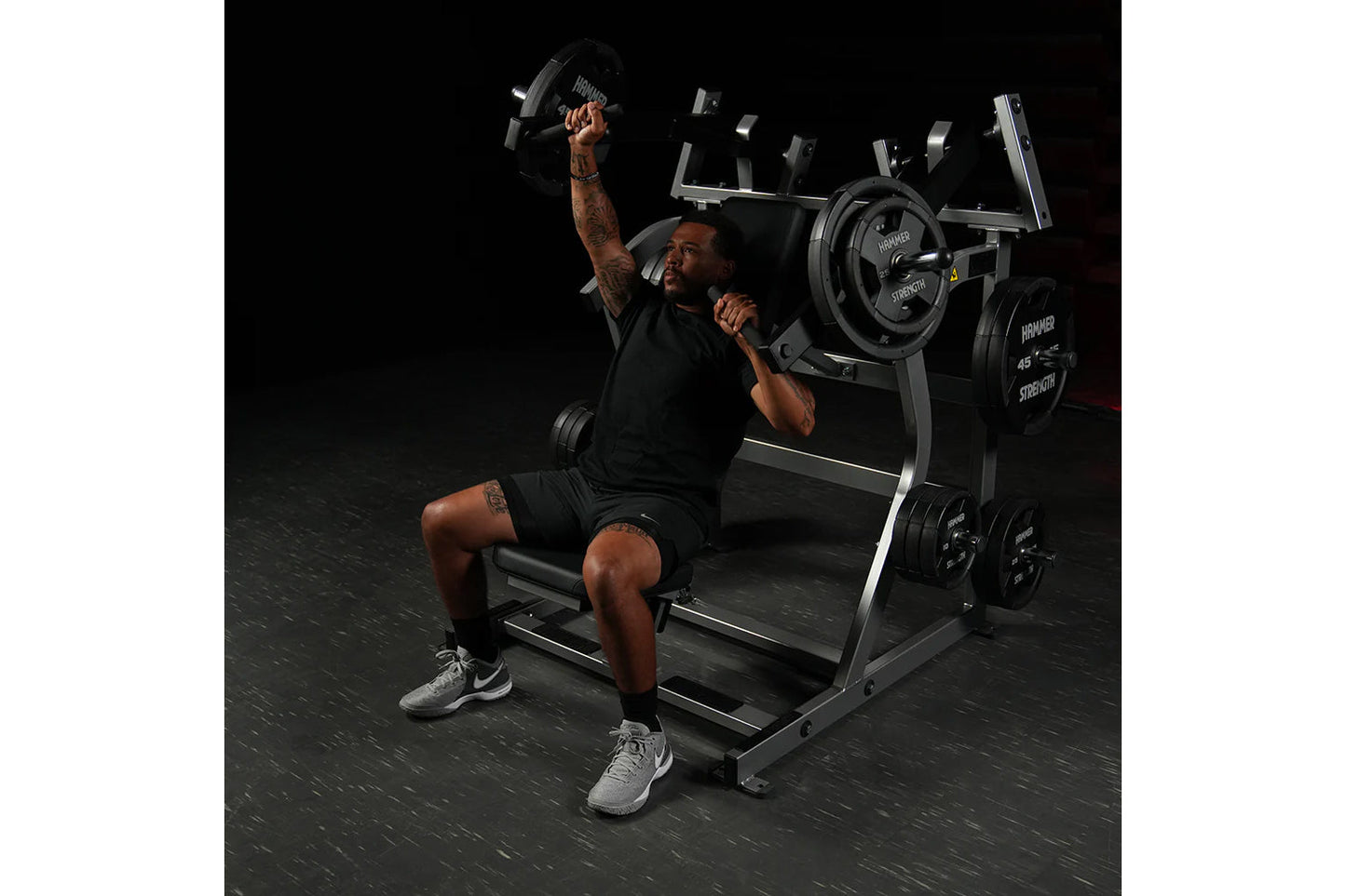Man using black and silver Hammer Strength plate-loaded iso-lateral super incline press with dumbbells in gym setting