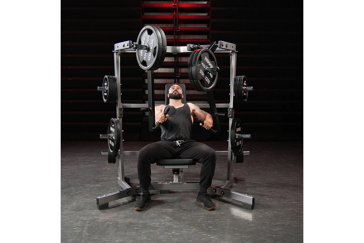 Man using black and silver plate-loaded chest press machine with weighted plates in gym setting