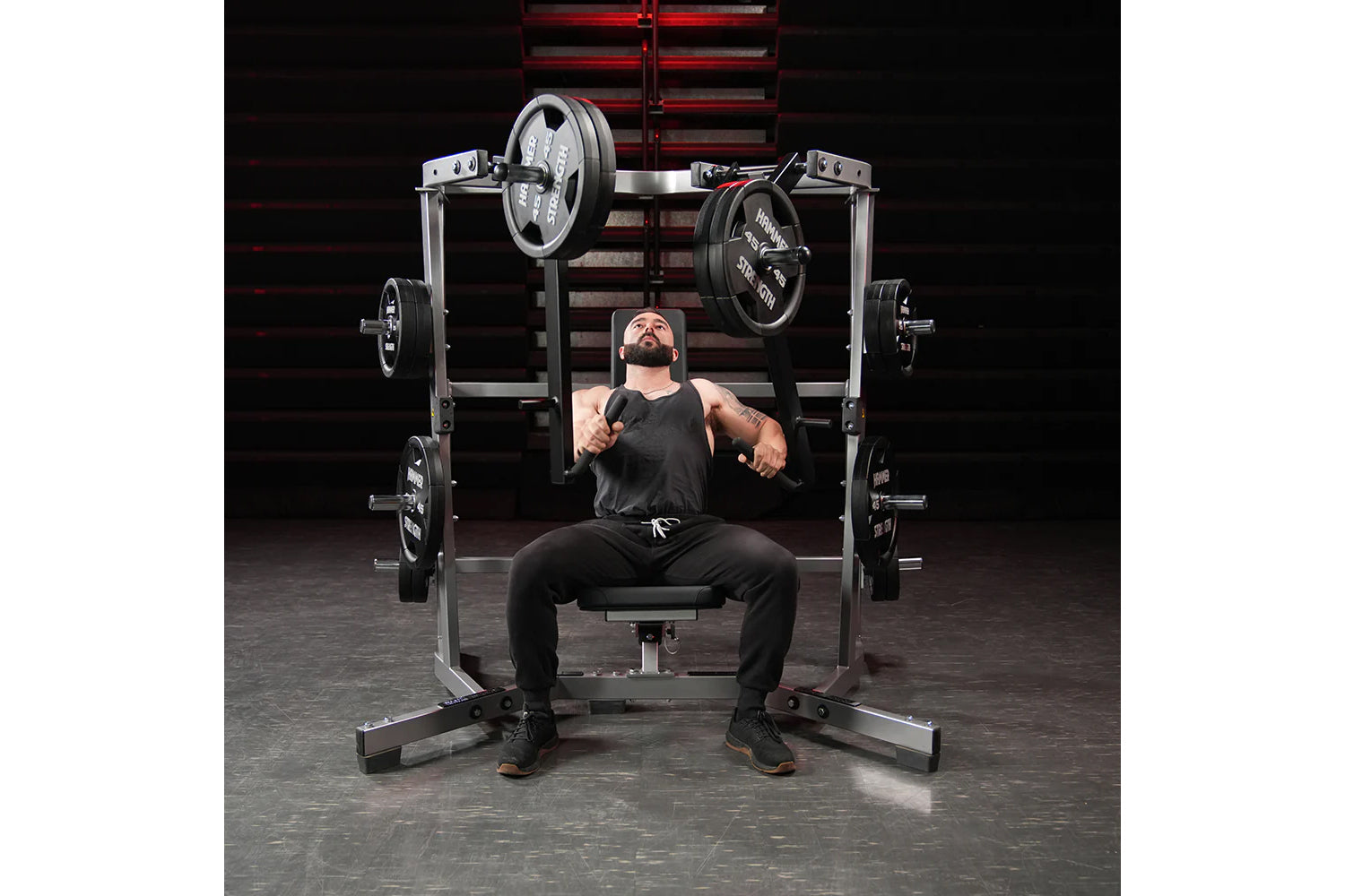 Man using black and silver plate-loaded chest press machine with weighted plates in gym setting